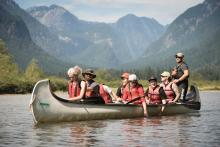 group of young people canoeing in water surrounded by mountains
