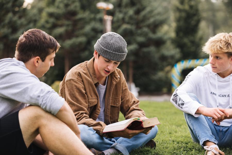 men reading a book together outside