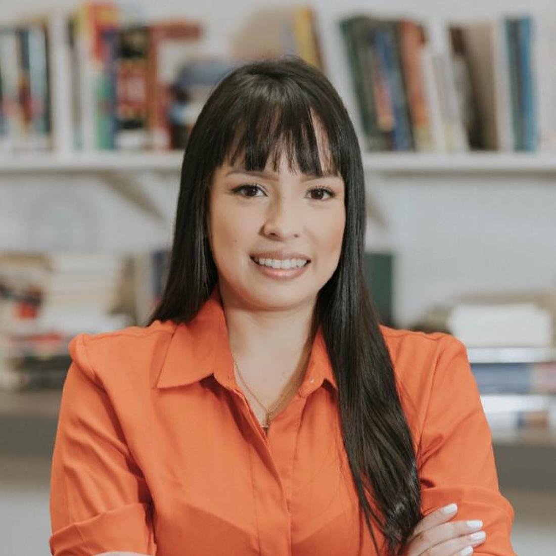 Tatiana Ortiz standing in front of a bookshelf smiling