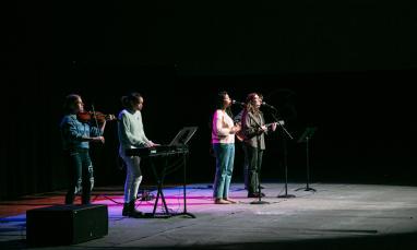 TWU's chapel worship band on stage in the gym. There are instruments and purple lights.