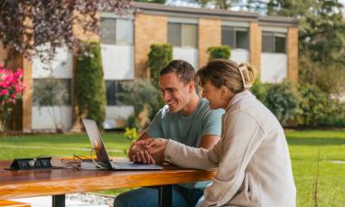 Students looking at laptop outdoors