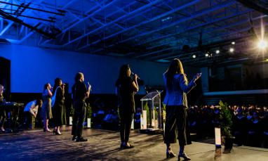 people standing on stage in gym signing