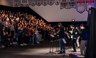 people in bleachers of gym with band playing music