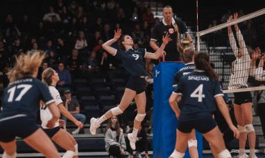 female volleyball player in the air hitting the ball