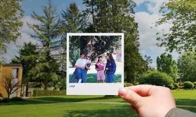 persons hand holding a Polaroid photo outside in front of tree