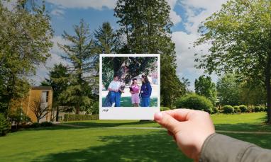 person's hand holding Polariod photo in front of green space