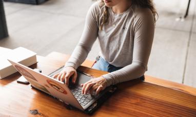 woman using laptop outdoors on wooden table