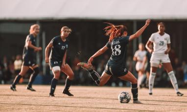 female student athletes playing soccer on field