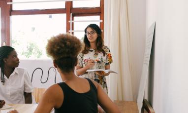 woman presenting to other people sitting at a table