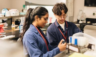 Two students in a lab looking at a machine