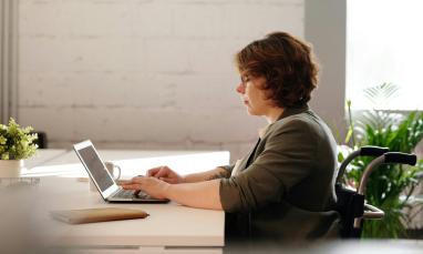women in a wheelchair sitting at desk and working on a laptop