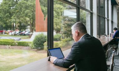 man working on computer in front of large windows