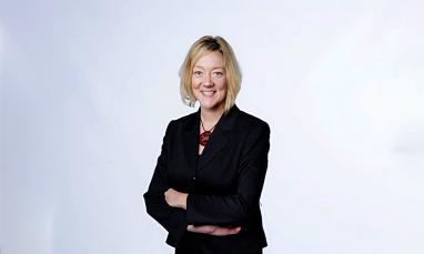 woman standing in front of white background with arms folded