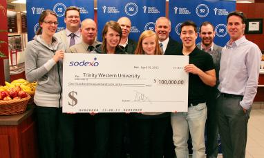 A group of people standing with a cheque.