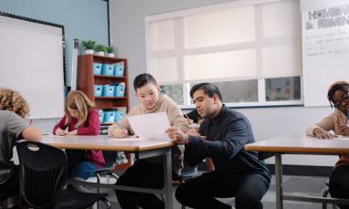 A teacher assisting a student by the child's desk.