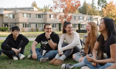 A group of people sit in a circle on the grass.