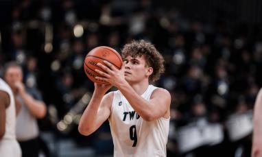 A basketball player in a white "TWU" jersey with number 9 prepares to shoot.