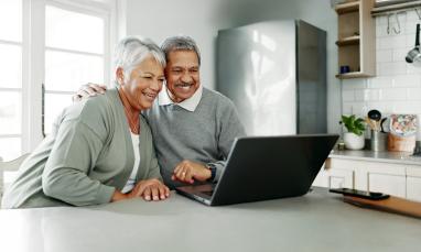 Elderly couple smiling and viewing laptop together at a table