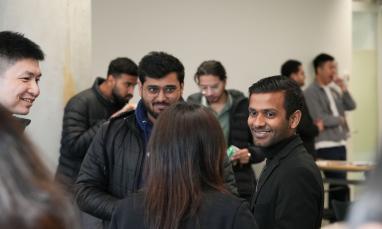 Group of people smiling and chatting in a hallway.