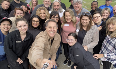 Group of smiling adults posing outdoors.