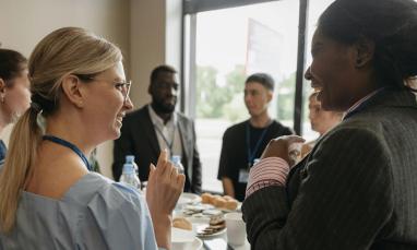 People in business attire chatting and smiling at a networking event.