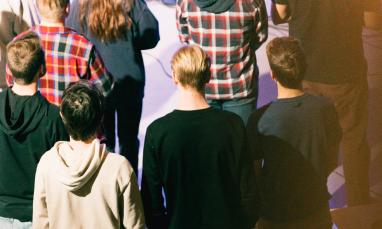 Crowd of people standing in a dimly lit room.