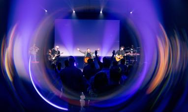 Concert with vibrant lights and audience, musicians performing on stage.