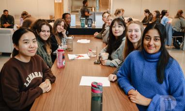 People smiling and sitting at a table in the Global Lounge