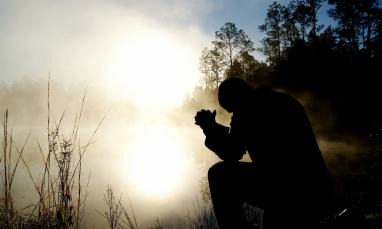 person praying by a lake
