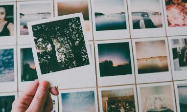 stock photo of Polaroids with a hand holding one in front of a larger collection