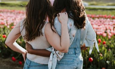 Two women embracing each other in a field of flowers.