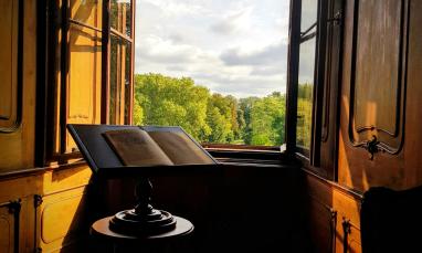 stock photo of book on stand in front of an open window in a grand room