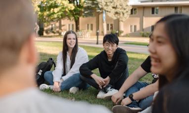 group of students sitting outside on the grass