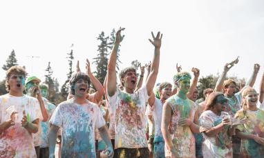 group of people covered with coloured chalk cheering