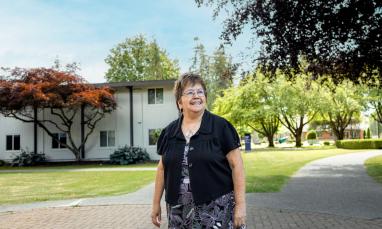 Patti Victor Switametelót on campus in front of Douglas Centre with a blue sky and trees behind her
