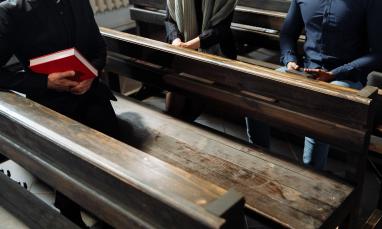a person holding a book sitting on a bench in the church