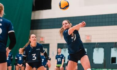 Women in blue jersey playing volleyball