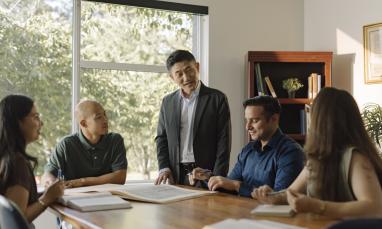 A faculty member leading a discussion with students seated around a table.