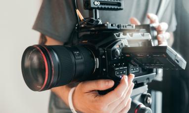 A professional video camera being operated by a person during filming.