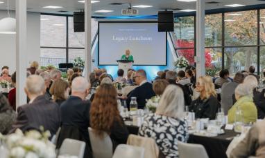 Guests seated at tables in Trinity Commons during Trinity Western University’s Legacy Luncheon, with a speaker presenting at the podium.