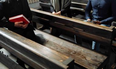 a person holding a book sitting on a bench in the church