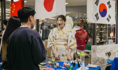Students engaging at a cultural booth decorated with international flags during a TWU Culture Week event.