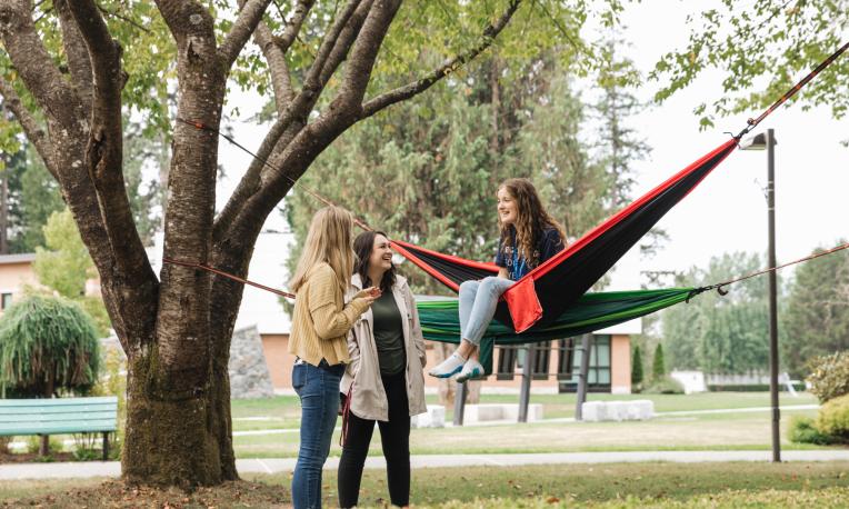 Students on Langnley campus in hammocks talking.