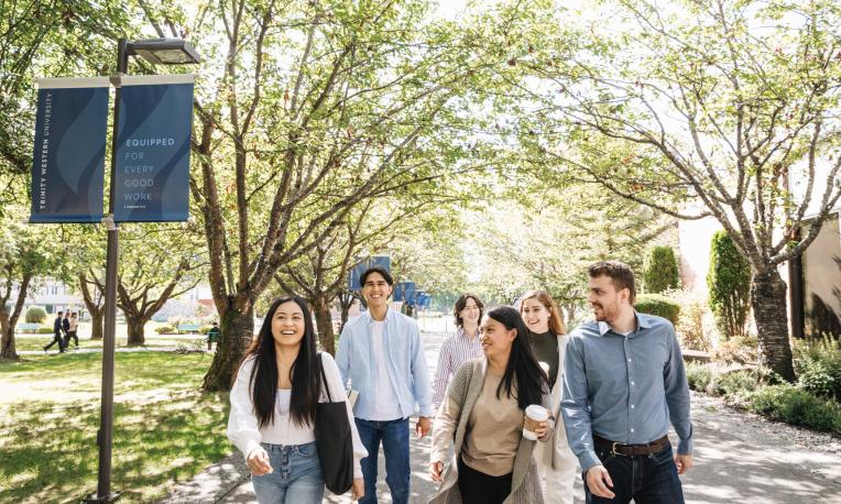 Students walking down main pathway at TWU smiling and talking.