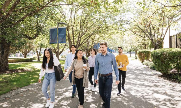 Students walking down main pathway at TWU smiling and talking.