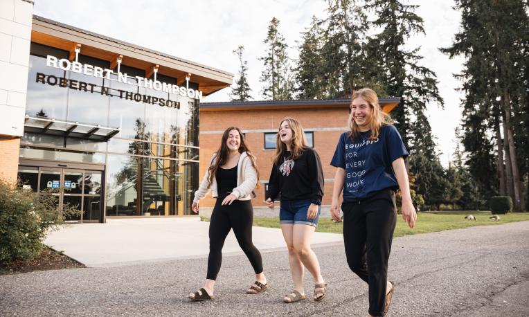 Three students happily walking past Robert N. Thompson