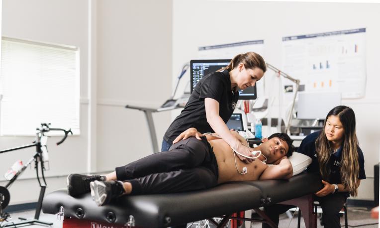 Professor teaching student with live patient on table