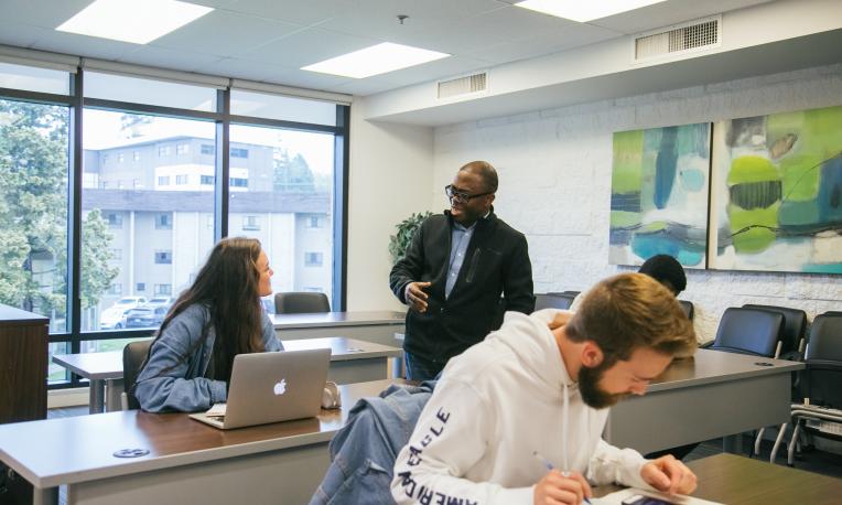 Professor teaching in classroom with three students