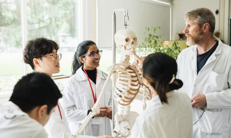 Students in class with professor looking at a skeleton