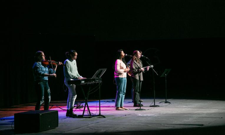 TWU's chapel worship band on stage in the gym. There are instruments and purple lights.